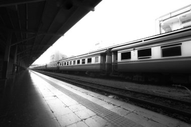 Yolcu trenlerinin park edildiği siyah beyaz tren istasyonu platformu