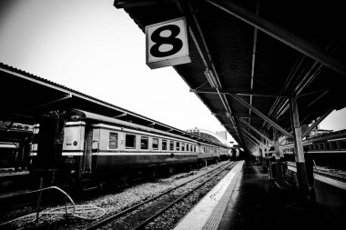 Yolcu trenlerinin park edildiği siyah beyaz tren istasyonu platformu