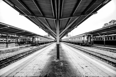 Yolcu trenlerinin park edildiği metal platformlu siyah beyaz tren istasyonu platformu.
