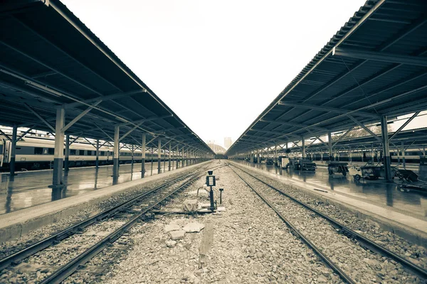鉄道駅の屋根を持つ黒と白の鉄道線路やプラットフォーム — ストック写真