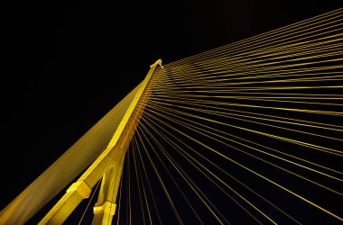 Kablolar gece parlak ışıklarla büyük bir köprüyü gerer. Karınca bakışı.