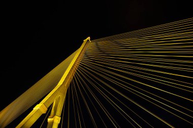 Kablolar gece parlak ışıklarla büyük bir köprüyü gerer. Karınca bakışı.