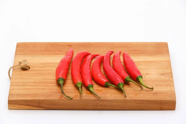 Closeup fresh Red hot chilli peppers on wooden cutting board and isolated on white background