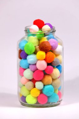 Beyaz arka planda cam şişede renkli ponpon.