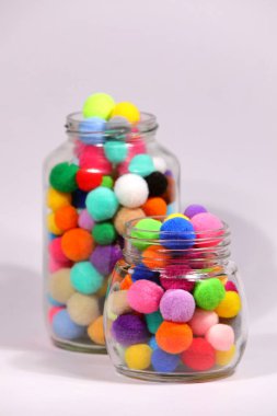 Beyaz arka planda cam şişede renkli ponpon.