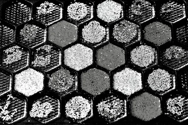 Black and white Closeup very small multicolored plastic panels placed in plastic mold on dark background