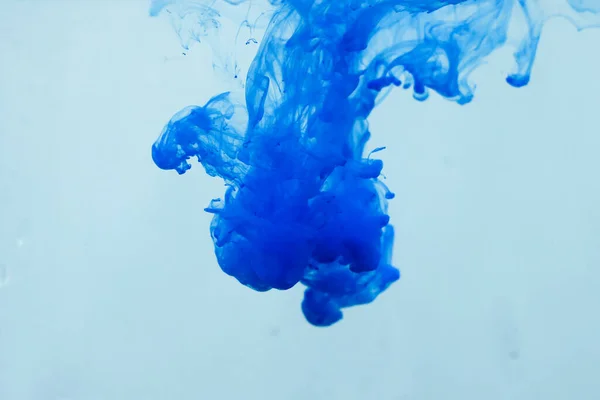 Colors dropped into liquid in motion. Ink swirling in water. Blue ink in water, abstract background