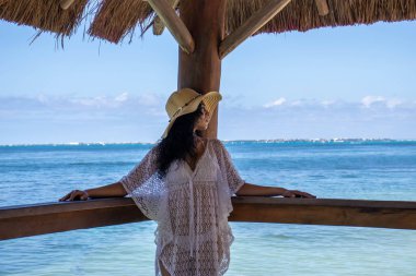 Dünyanın en romantik, rahatlatıcı, güzel ve çekici denizlerinden biri olan tropik Karayipler 'in turkuaz denizi üzerinde bir iskelede uzanan genç kadın..