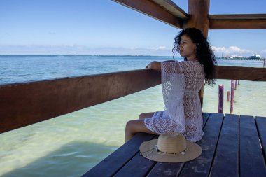 Limanda mutlu mesut oturan seksi genç kadın denizin turkuaz renginin ve Karayip güneşinin tadını çıkarıyor. Burası ideal bir tatil ve yaz turizmi noktası..