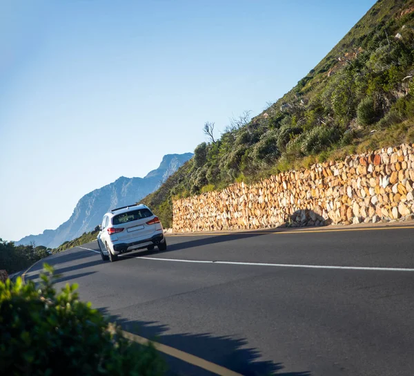 Car driving along the garden road and clarence drive in an area known as gordon bay\'s in South Africa, this is a road that runs along the coastline of the fynbos coast.