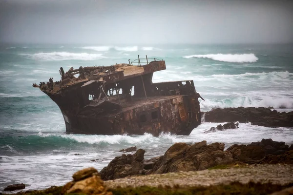 Sunken ship stranded at Cape Agulhas in South Africa, this place divides two oceans. It divides the Atlantic Ocean from the Indian Ocean and it is deep and rough waters.