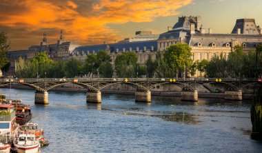 Fransız şehri Paris 'teki Seine Nehri üzerinde Pont des Arts ile güzel bir günbatımı ve arka plandaki müze Seine Nehri bu güzel Avrupa şehrini bölüyor..