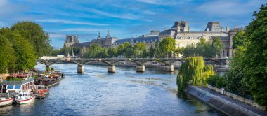 Paris 'teki Pont des Arts' ın panoramik manzarası. Louvre Müzesi, Paris 'i gökyüzü altında ve lacivert bir su üzerinde ikiye bölen Seine nehri üzerindeki köprünün arkasında. Paris Köprüsü.