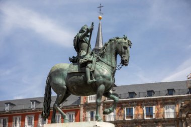 İspanya Kralı III. Philip 'in heykeli, Madrid' in efsanevi ve ünlü meydanında arka planda güzel bir cephe ile İspanya 'daki gezginler ve turistler için en ikonik yerlerden biridir..