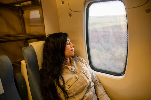 Young female traveler enjoying travel. Pretty young woman traveling with classic train sitting near the window. Travel concept, transportation.