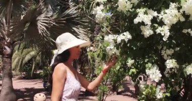 Marakeş, Fas 'ta Fransız göçmen tarafından tasarlanan bir botanik bahçesi olan Majorelle Bahçesi' nin çiçeklerinin ve bitkilerinin kokusunu alan, gezen, eğlenen ve koklayan turist kadın..