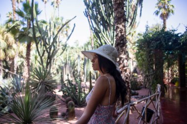 Berber Majorelle bahçesinin keyfini çıkaran şapkalı güzel bir turist. Marakeş 'te (Fas) Fransız göçmen sanatçı Jacques Majorelle tarafından tasarlanmış bir botanik bahçesi..