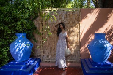 Ahşap bir duvarda genç bir turist ve Marakeş 'teki Majorelle bahçesinin mavi bir çevresi (Fas)).