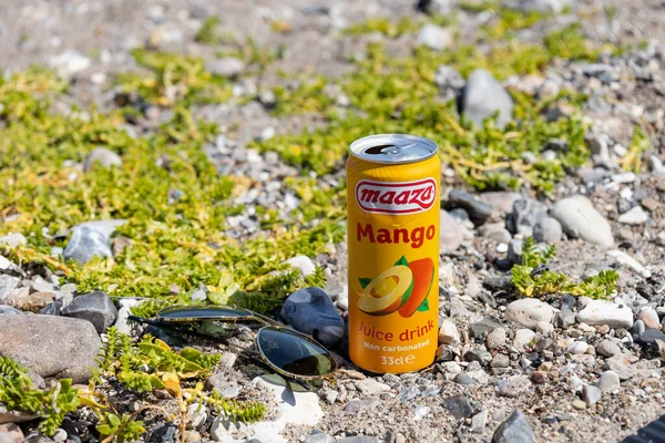 Orange can with mango juice on the small stones on the beach by the sea. High quality photo