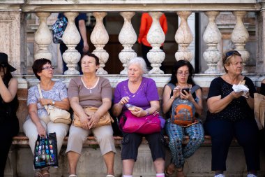 Turistler çok yoğun turizm sezonunda St. Marks Meydanı 'nda bir oturma alanına mola veriyorlar.