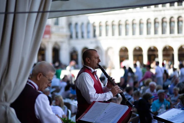  St. Marks meydanında toplanan turistlere müzik çalan müzisyenler müziği her gün Quadri, Lavena ve Florian restoranlarında çalıyorlar. 