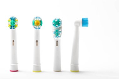 Dört elektrikli diş fırçası başlığı dikildi. Biri yan tarafa bakıyordu. Beyaz arka plandan izole edilmişti.