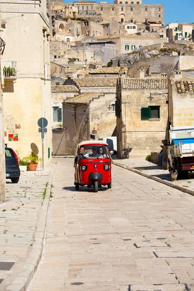 Bari Matera İtalya-23 Eylül 2015 kırmızı bir Piaggio üç tekerlekli araç Matera 'da antik bir caddede seyahat ediyor. 