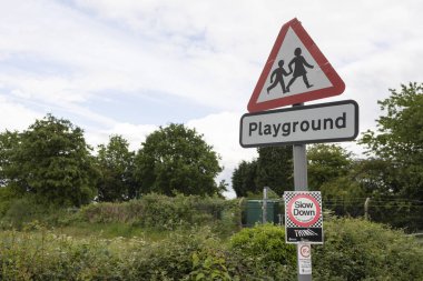  A British road sign signifying children going to or from school or a playground ahead. The sign is fixed to a lamppost 