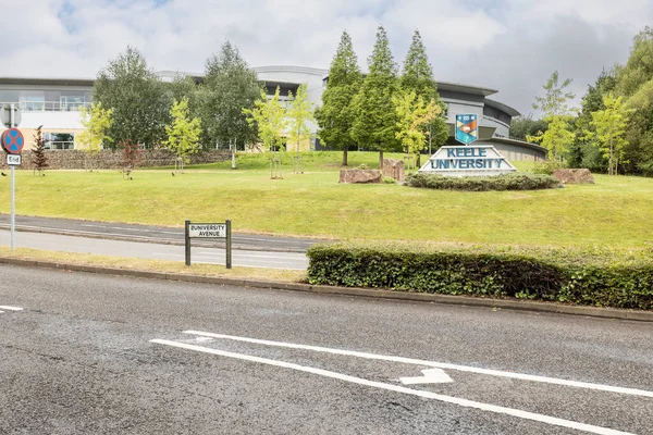 Newcastle-under-Lyme, Staffordshire birleşik krallığı Nisan 14, 2022 Keele Üniversitesi logosu ve üniversite caddesi boyunca yol girişindeki binalar