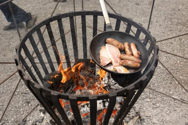 cooking breakfast on a open wood fire bacon and sausages
