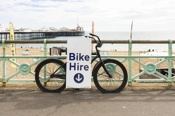 Hırpalanmış ve soyulmuş eski bir bisikletin üzerinde kiralık bisiklet tabelası.