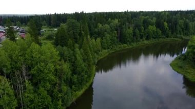 Yazın, ormanın yanındaki gölün üzerinden kalkan bir drone 'dan ateş etmek, ufuktaki ahşap evler ve ormanlar.