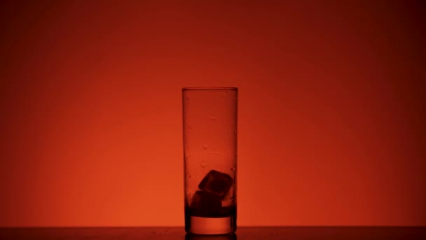 Παγάκια Πέφτουν Ένα Ποτήρι Στο Κόκκινο Φόντο Σιλουέτα Αργή Κίνηση — Αρχείο Βίντεο