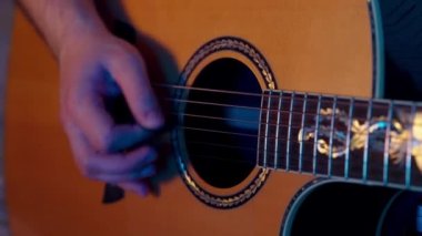 Gitarist gitar penasıyla akustik gitar çalıyor.