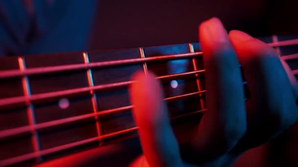 Közelkép egy férfi ujjairól, ahogy basszusgitározik.