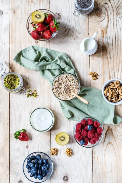 Concepto de desayuno saludable con copos de avena, frutas, yogur, nueces, bayas, semillas de chía — Foto de Stock