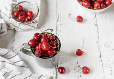 Beyaz ahşap arka planda peçeteli, ağlayıp sızlanan, gri kırsal fincanda tatlı kirazlar