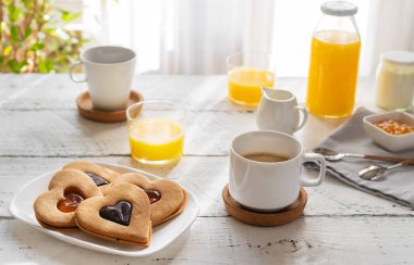 Kahveli kahvaltı konsepti, portakal suyu ve kalp şeklinde reçelli kurabiyeler.