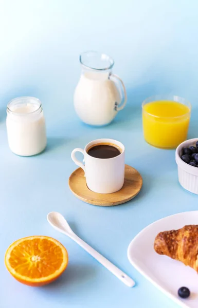 Conceito de café da manhã com xícara de café, croissant, leite, suco de laranja, iogurte e mirtilos — Fotografia de Stock