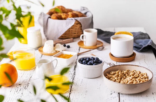 Concepto de desayuno con taza de café, croissants, aros integrales, leche, jugo de naranja, yogur y arándanos — Foto de Stock