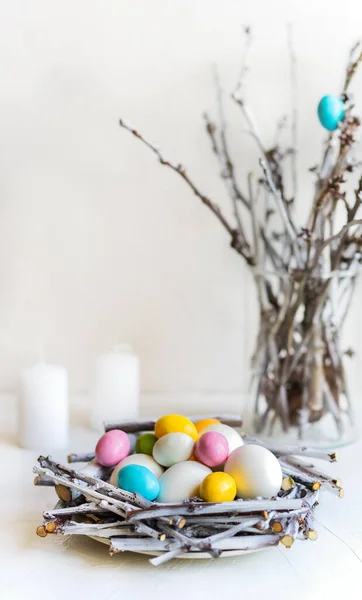 Composition de vacances pour Pâques. Nid avec œufs colorés et blancs, bougies, brunchs de printemps à l'arrière — Photo