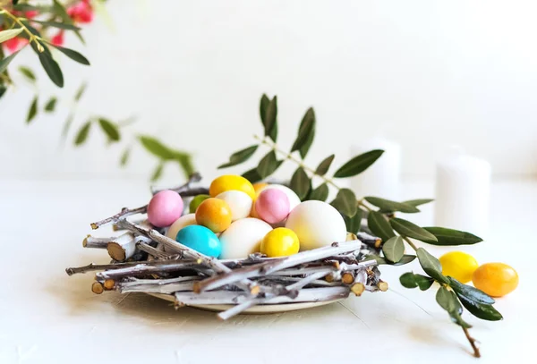 Composition de vacances pour Pâques. Nid avec œufs colorés et blancs, bougies, branche d'olivier et fleurs de printemps — Photo