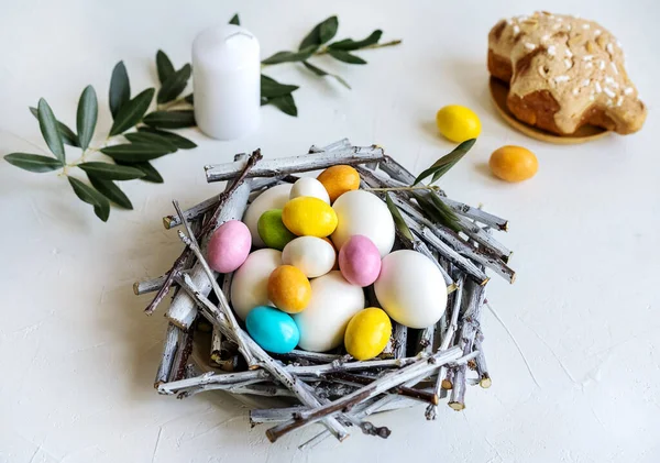 Composition de vacances pour Pâques. Nid avec couleur et œufs blancs, bougie, branche d'olivier et colomba — Photo