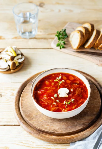 Kasede mantarlı pancar çorbası, ekmek, ahşap zeminde bir bardak su.