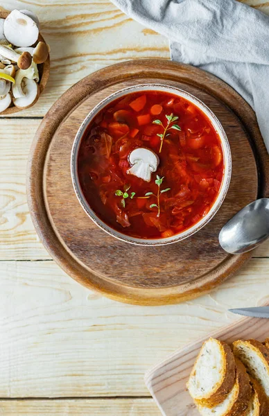 Kasede mantarlı pancar çorbası, ekmek, ahşap arka planda çiğ mantar.