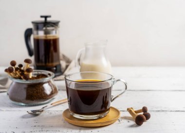 Sağlıklı moda kahve, fincanda mantar, kahve demliği, beyaz ahşap arka planda süt.