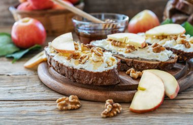 Süzme peynirli ekmek dilimleri, bal, elma ve fındık