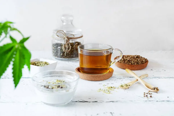 Prodotti di canapa: tè, semi sgusciati e interi, yogurt con semi, pianta di cannabis — Foto Stock