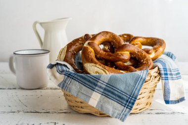 Süt kavanozu ve fincanla peçeteli ekmek sepetinde Brezels veya pretzels