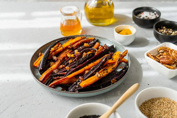 Roasted glazed spicy violet and orange carrots with ingredients on grey background. Close up — Fotografie, imagine de stoc
